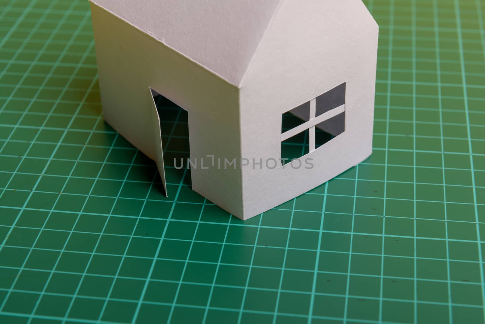 White family paper house over block of flats on yellow background paper. Minimalistic and simple concept, style. Copy space. Vertical orientation.