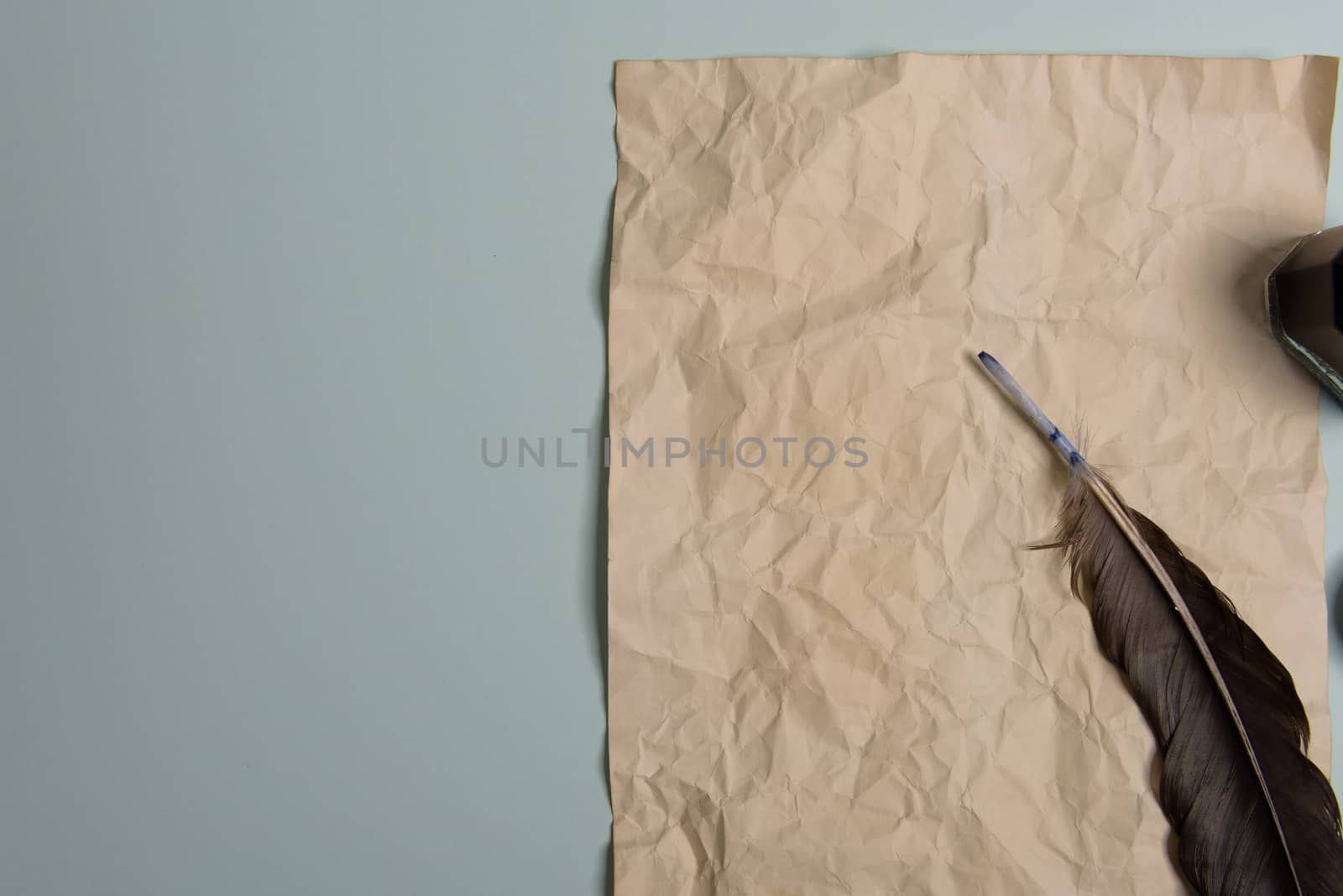 Raven feather, inkwell and old yellowed paper on red background. Copy space. Old letter.