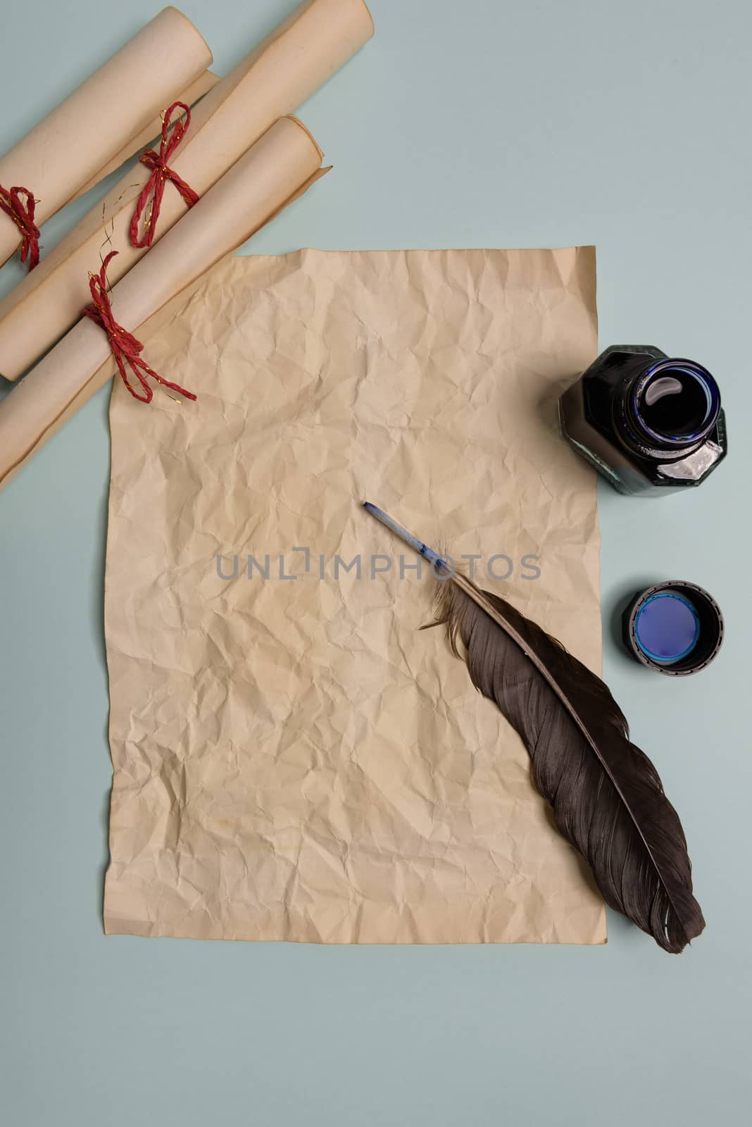 Raven feather, inkwell and old yellowed paper on red background. Copy space. Old letter.