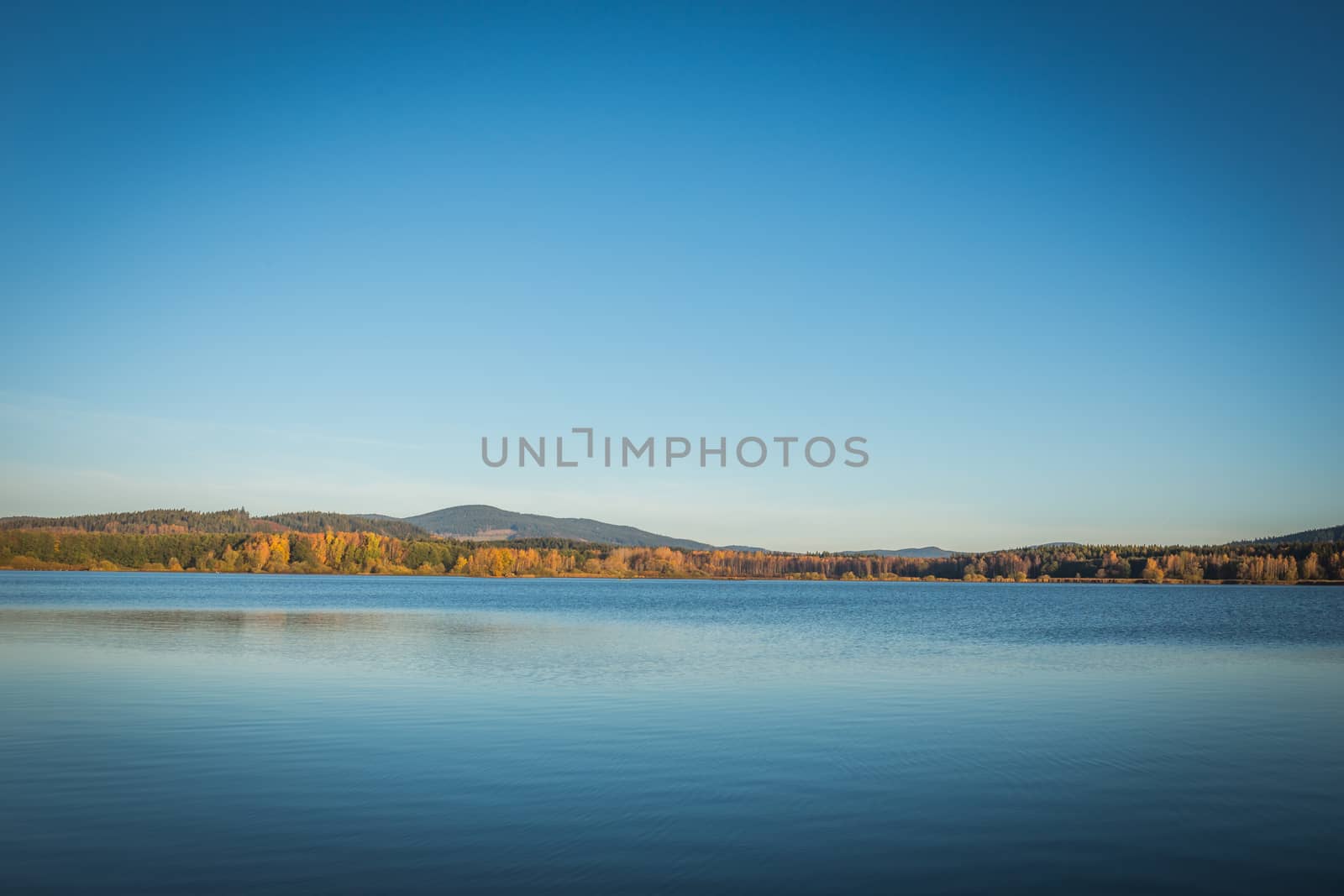 The Lipno Dam in a bright summer day. The lake is calm, has clean blue water. There are no clouds in the sky.