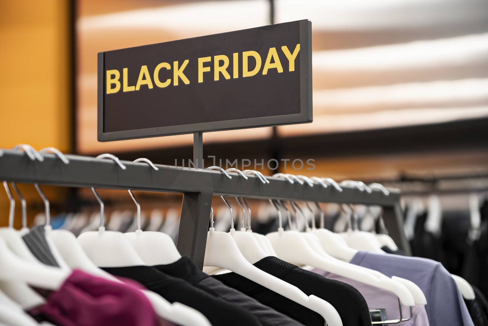 Big sale Black Friday. Discount season at the clothing store in the Mall. A row of hangers with colorful clothes. Blurred background.