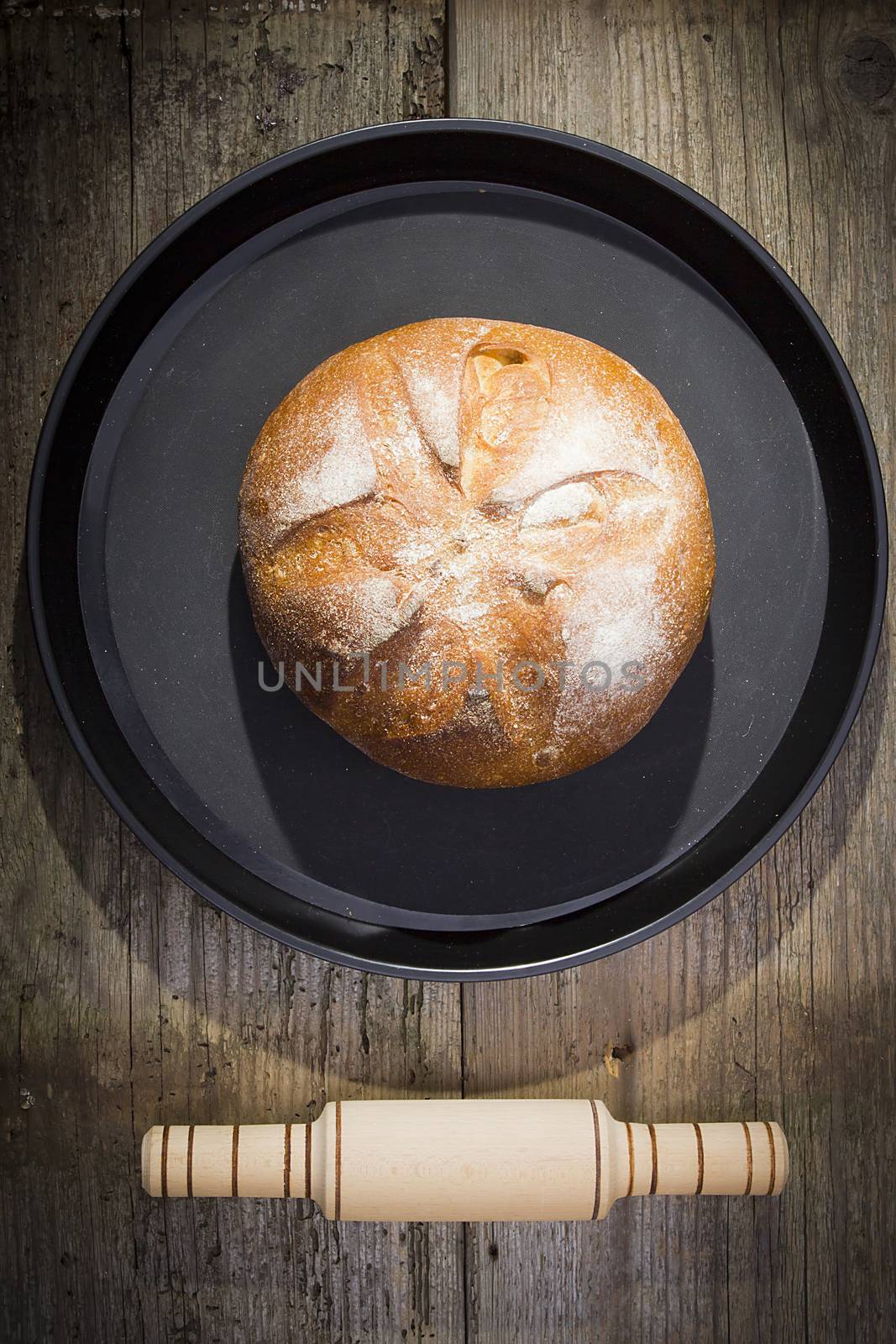 Loaf of bread on a round tray on a table from old boards