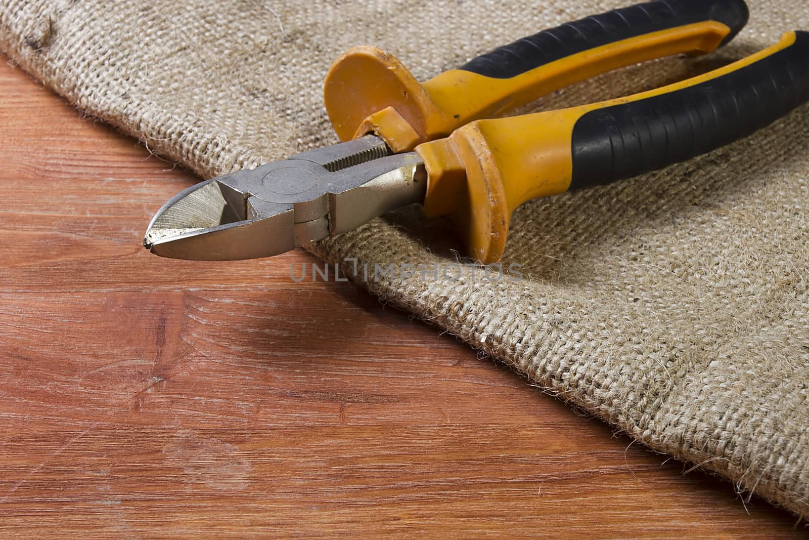 Wire cutters on wooden table laid by sacking