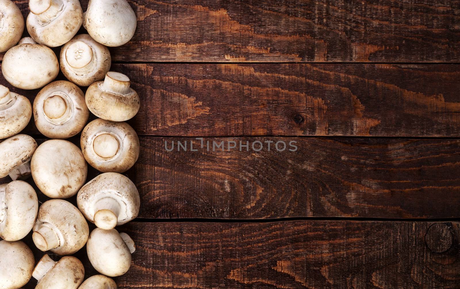 Heap of fresh champignon mushrooms on wooden table, top view. Copy space