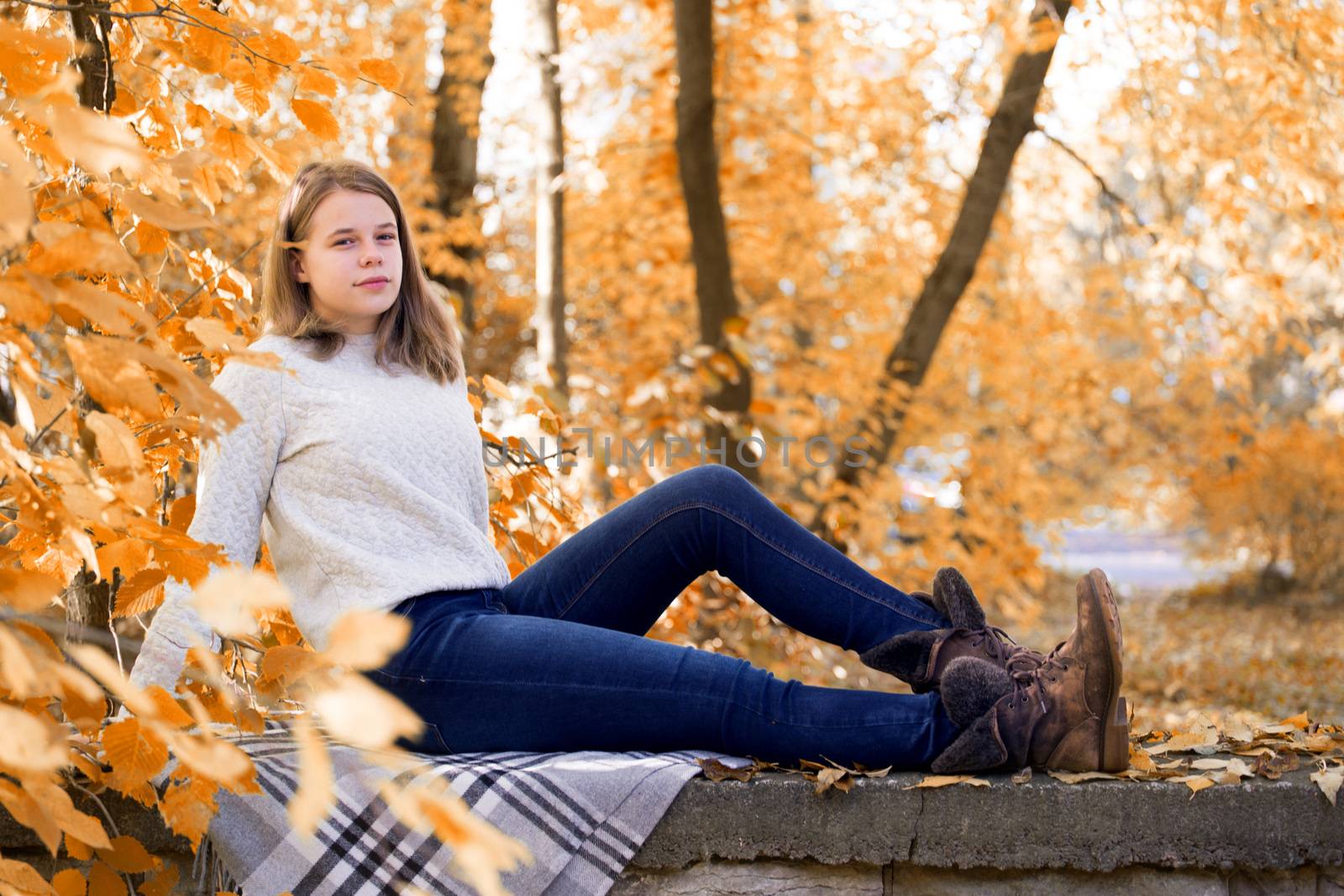 Teenage girl sitting in autumn garden by destillat