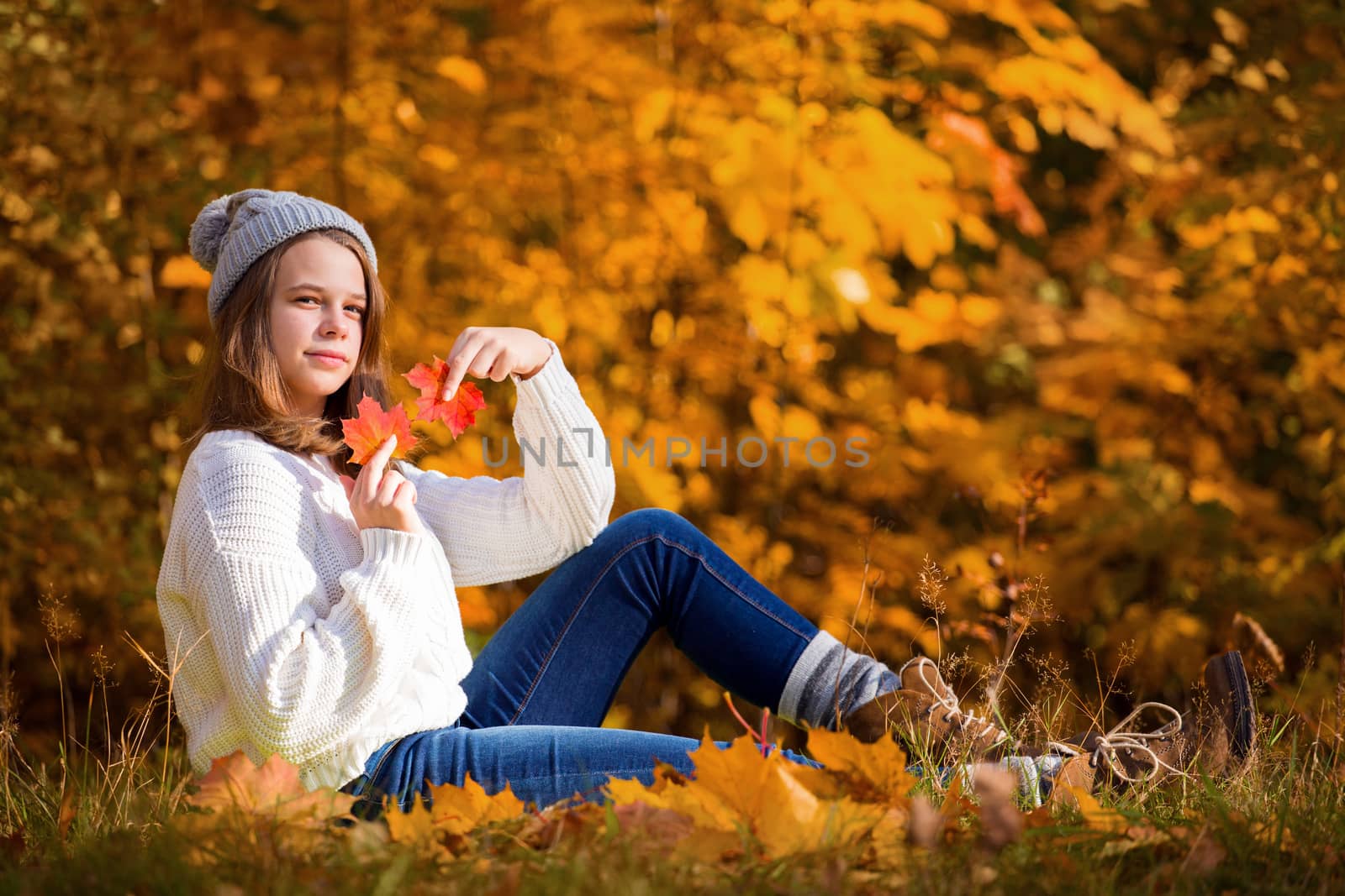 Portrait of pretty nice teenage girl sitting in autumn park , background with copy space for text