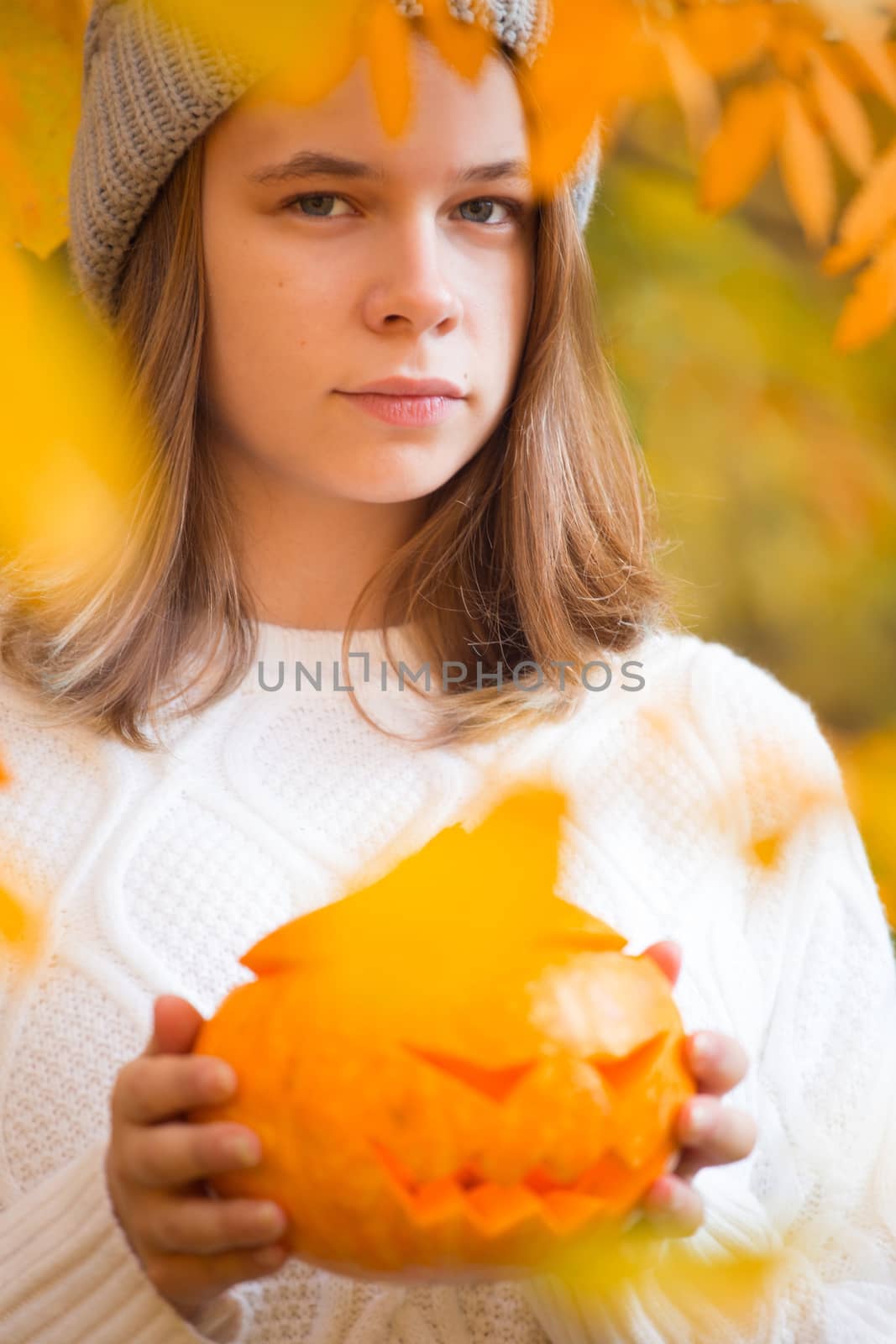 Teenage girl holding halloween pumpkin by destillat