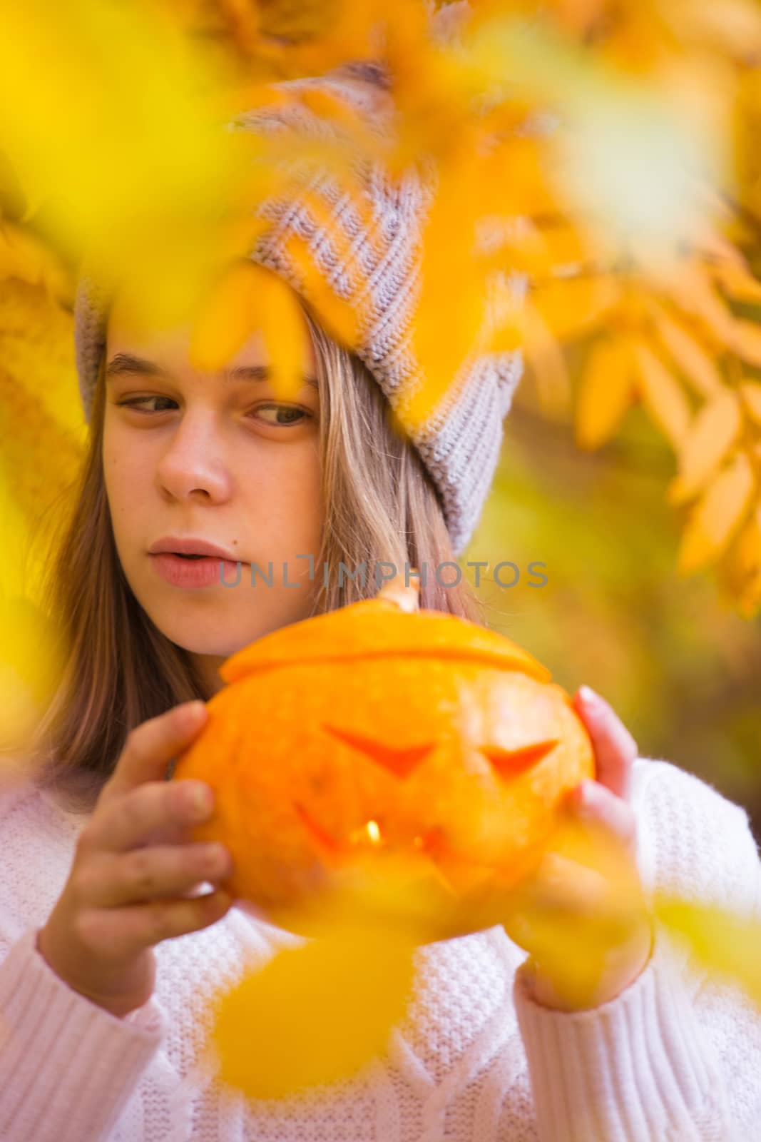 Teenage girl holding halloween pumpkin by destillat