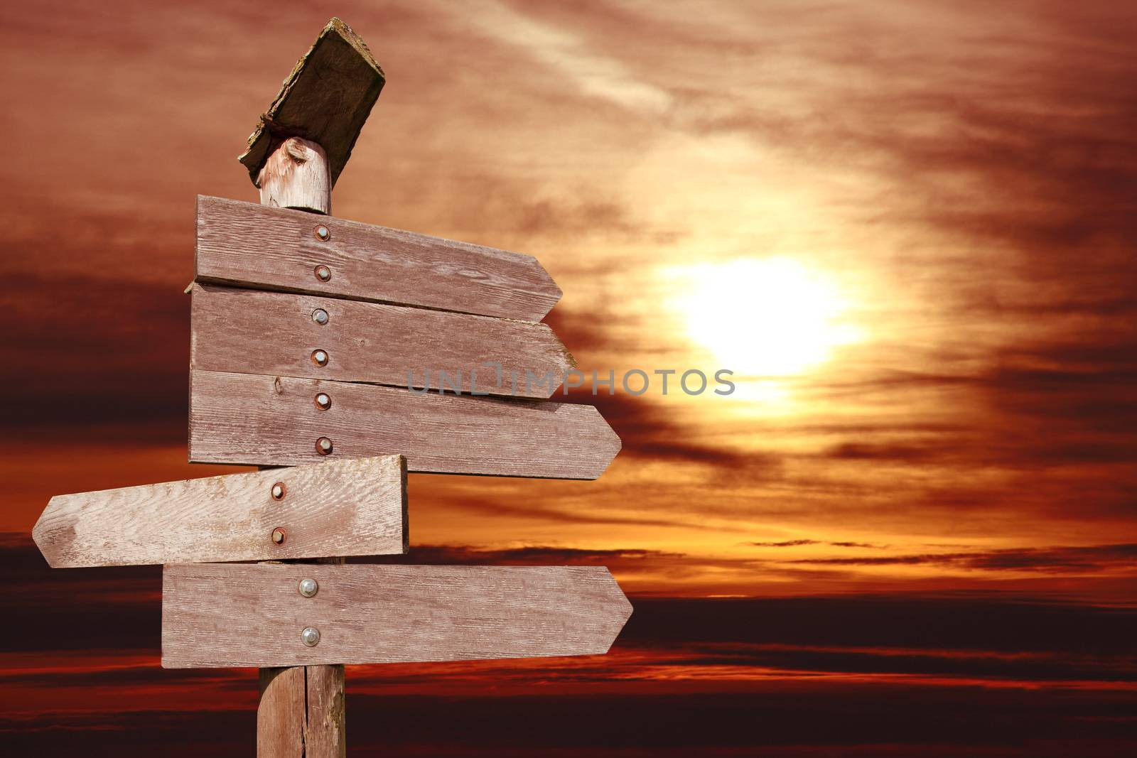 directional wooden arrows on sunset background