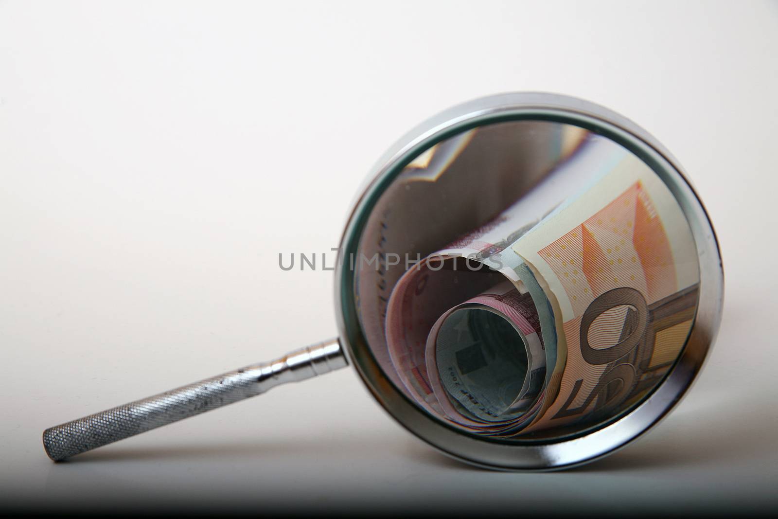 Money under magnifying glass on white background