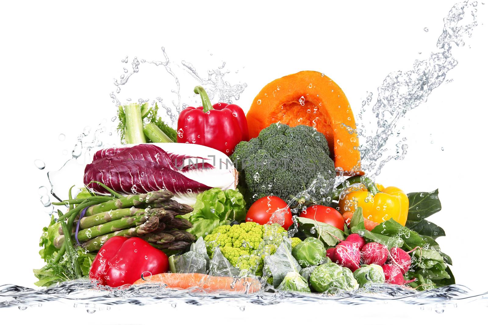 many fresh vegetables falling in water