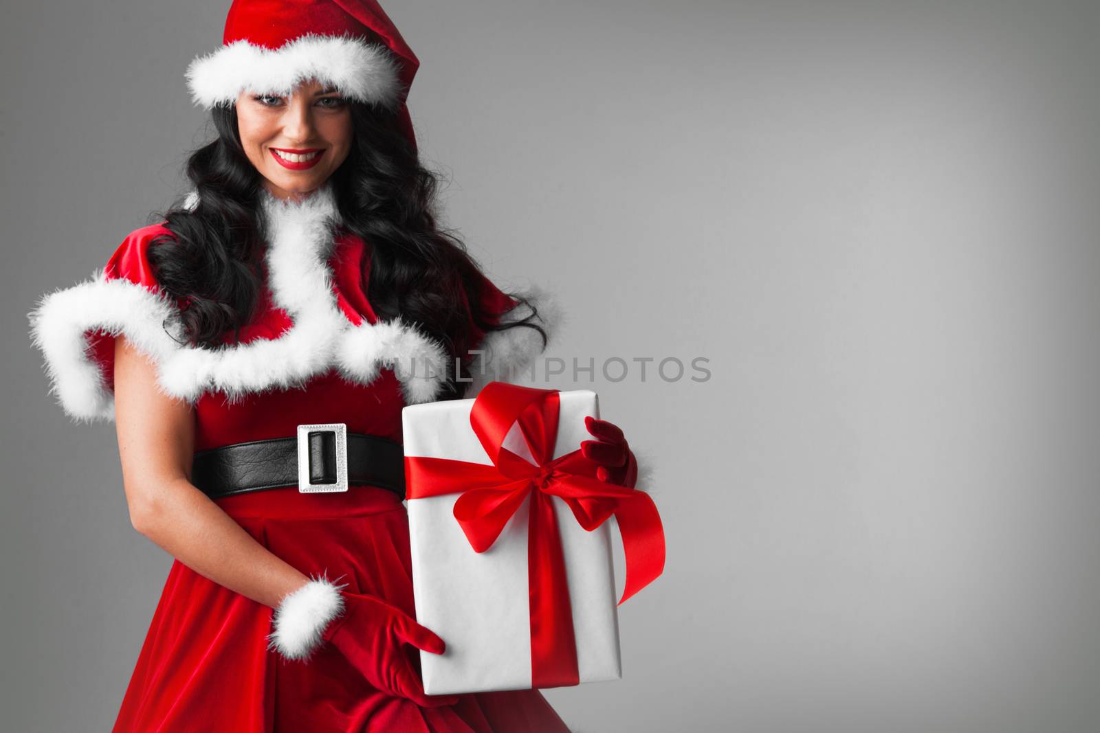 Woman in red Santa Claus outfit holding christmas gift box