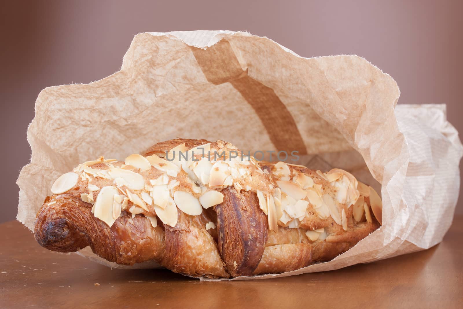 Fresh delicious golden almond crescent in paper bag by lanalanglois