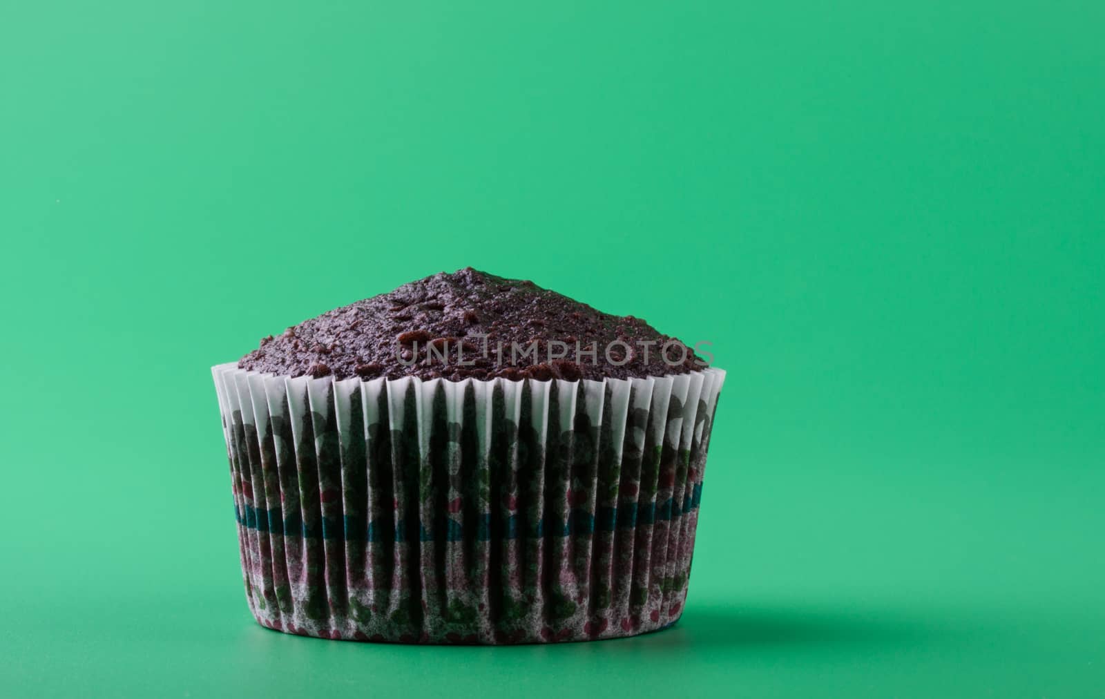 Delicious sweet chocolate cupcake without icing sugar, green background
