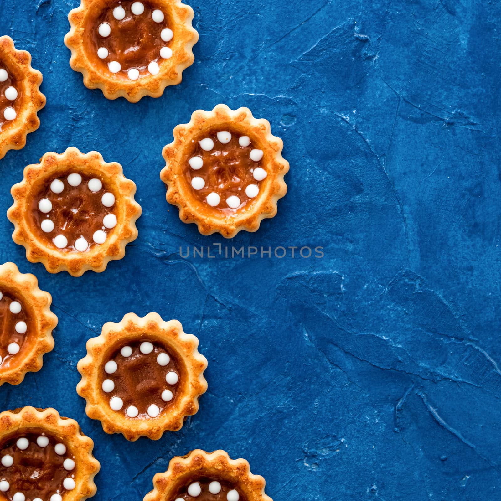 Cookies with caramel on trendy blue color 2020 textured background. Top view or flat lay. Color of 2020 food background and concept with copy space. Square