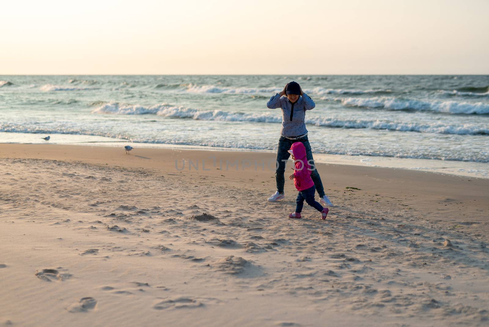 Mother and little daughter having fun on the beach. Authentic lifestyle image.