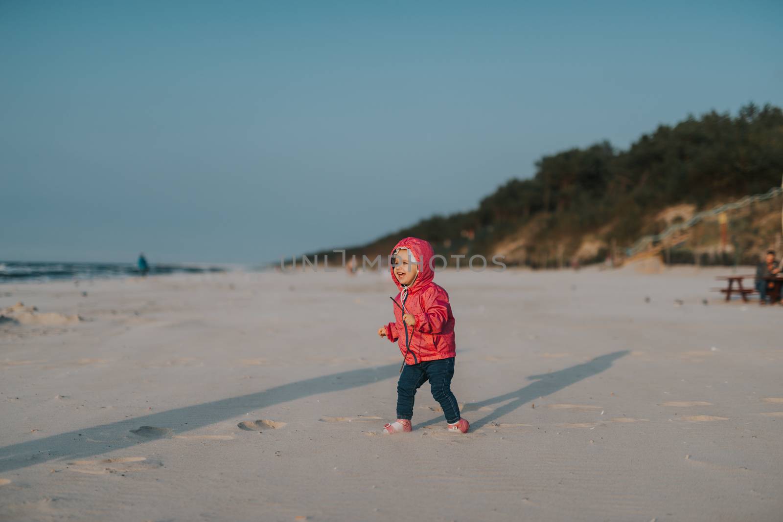 Adorable toddler girl on a sunny sand beach. Authentic lifestyle childhood image