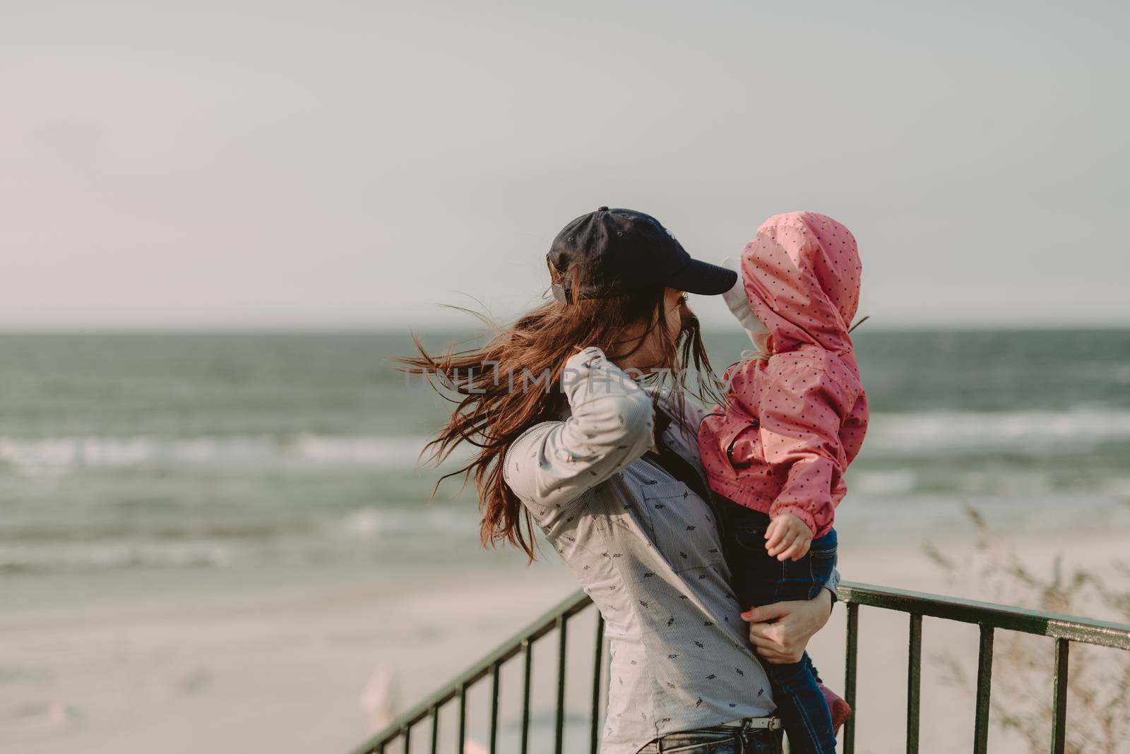 Mother and little daughter having fun on the beach. Authentic lifestyle image.