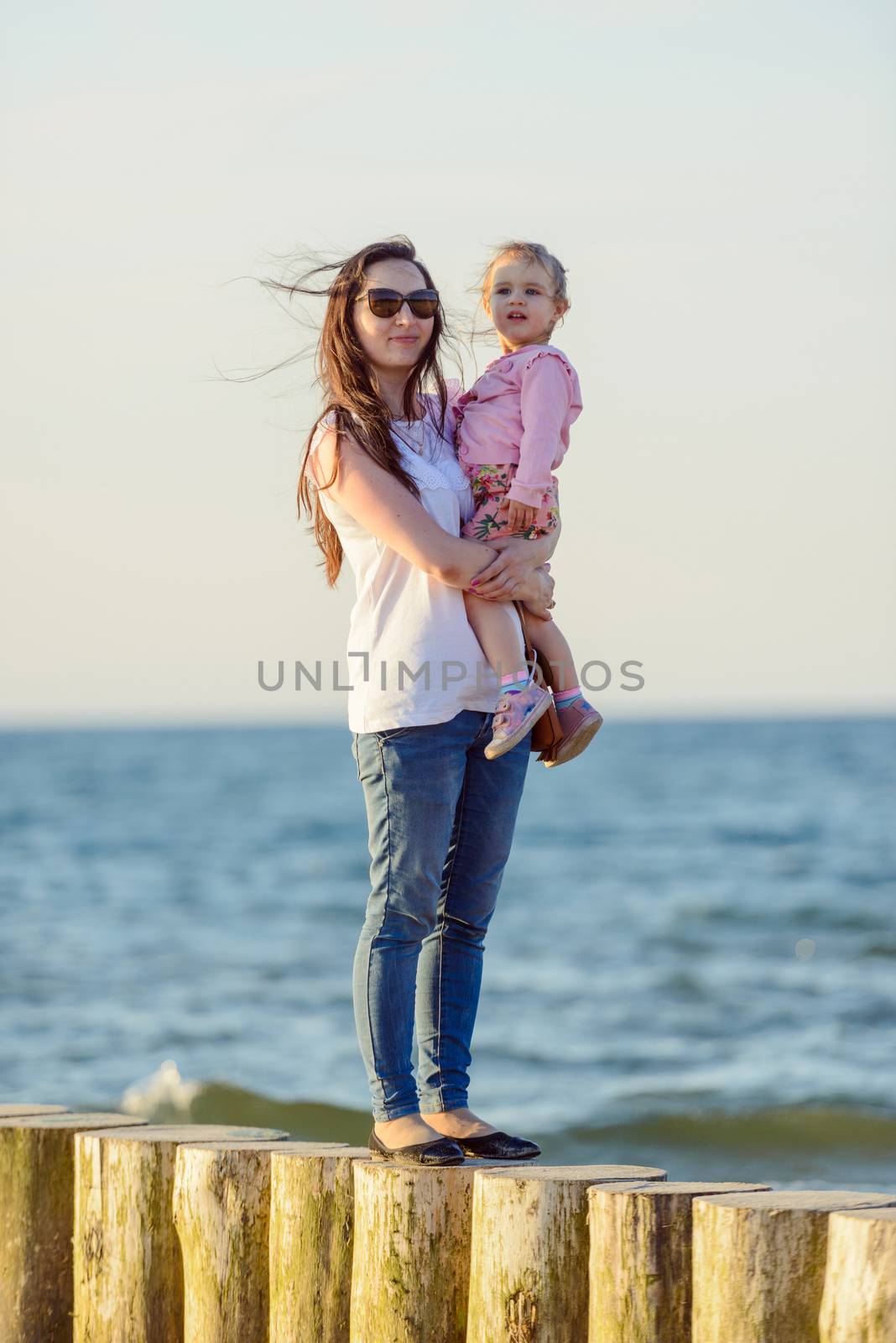 Mother and little daughter having fun on the beach. Authentic li by Brejeq