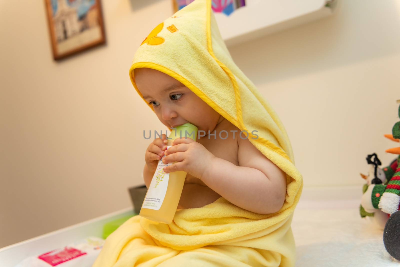 Adorable baby girl sitting under a hooded towel after bath.