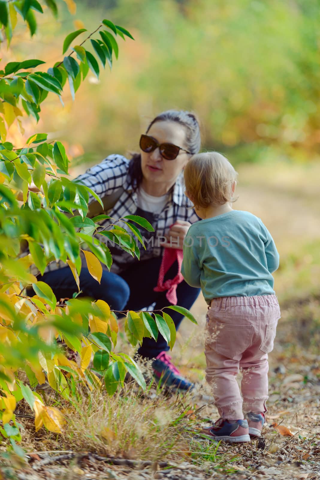 Happy mother and daughter in the park. Beauty nature scene with family outdoor lifestyle. Happy family resting together on the green grass, authentic lifestyle image