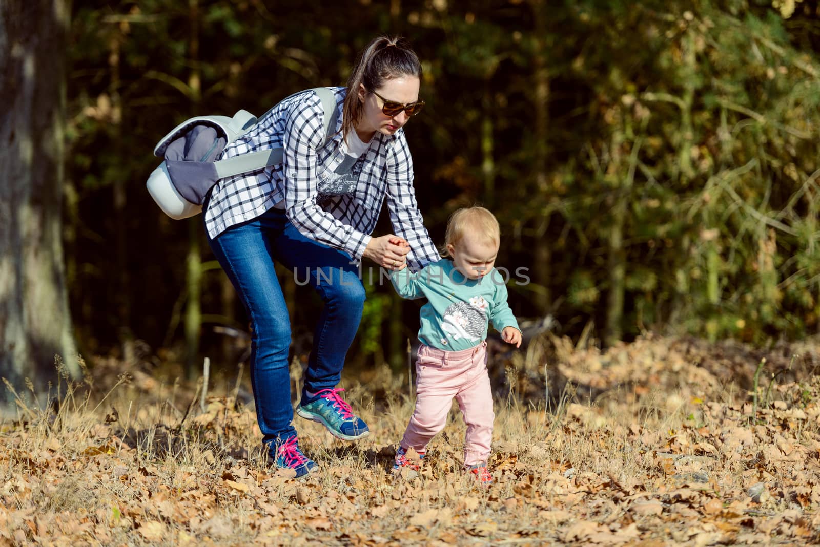 Happy mother and daughter in the park. Beauty nature scene with family outdoor lifestyle. Happy family resting together on the green grass, authentic lifestyle image