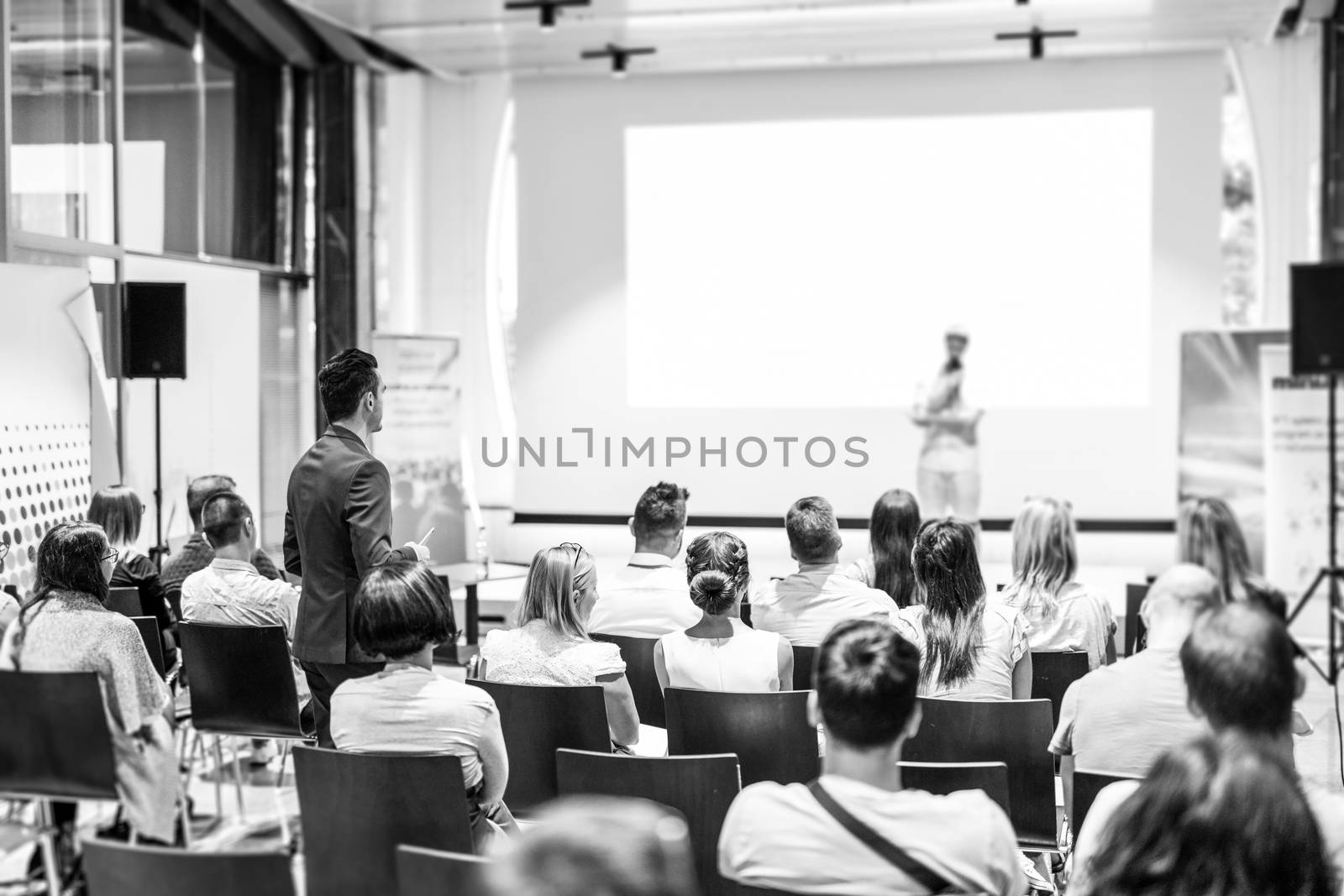 I have a question. Group of business people in conference hall. Businessman in audience standing and asking question to speeker. Conference and Presentation. Business and Entrepreneurship.