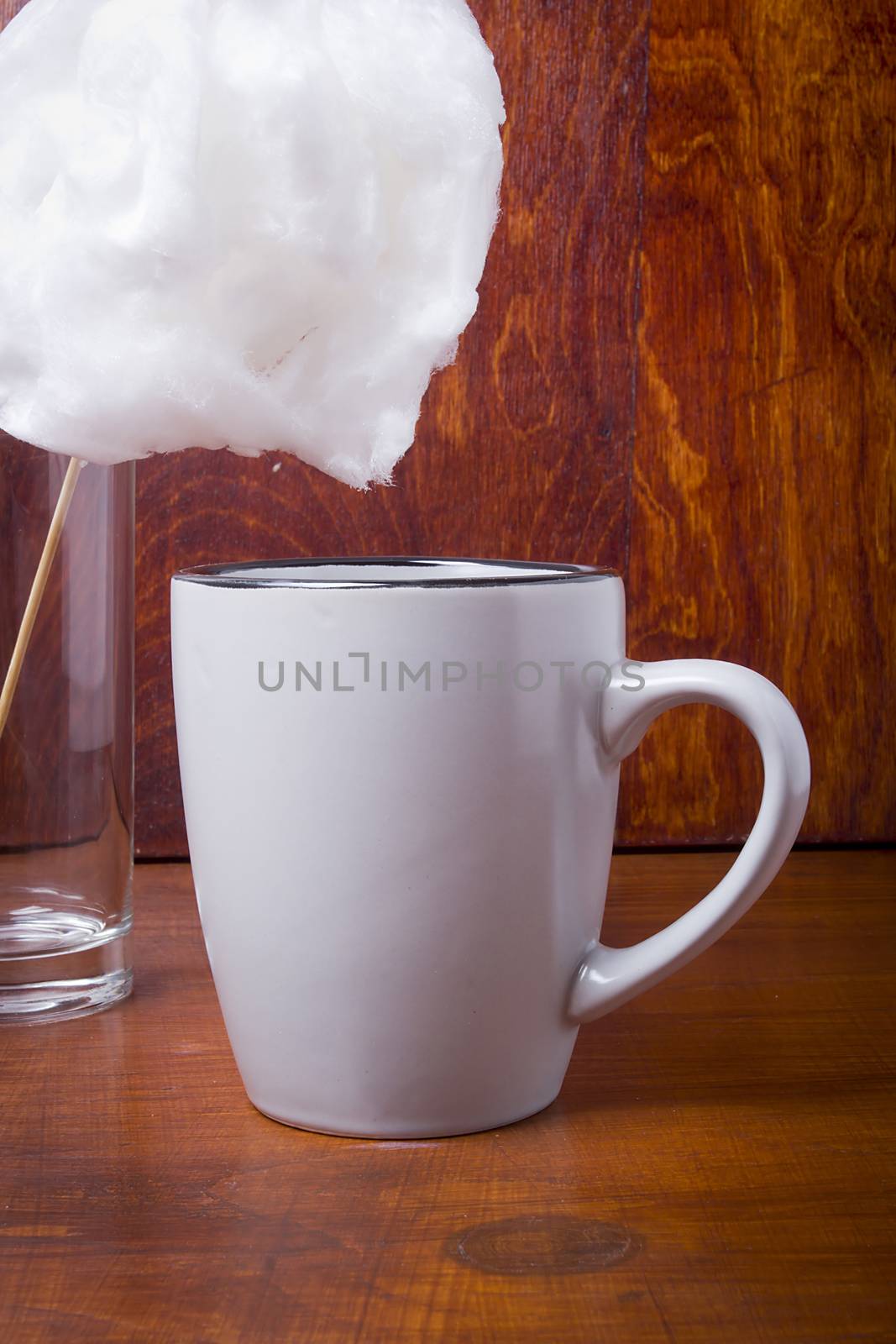 Cotton candy and cup with cocoa on a wooden table
