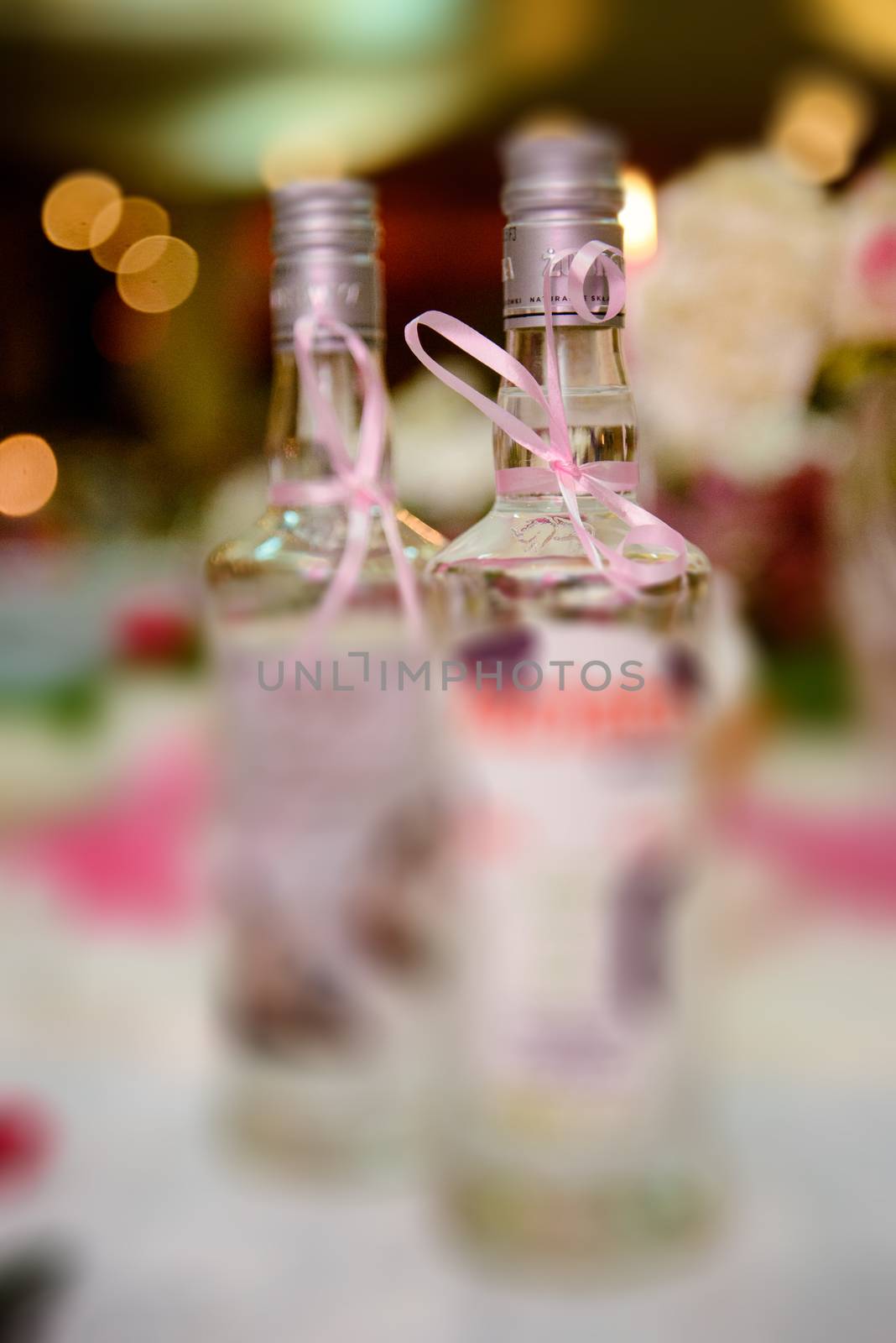 Bottle of cold vodka and wine bottle in bucket with ice and orange juice in jug on table, copy space. Alcohol bottles in ice bucket in restaurant. Wedding party