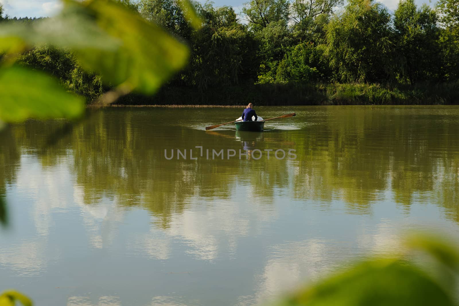 Bride and groom at a photo session in the nature. Newlyweds in the boat on the lake