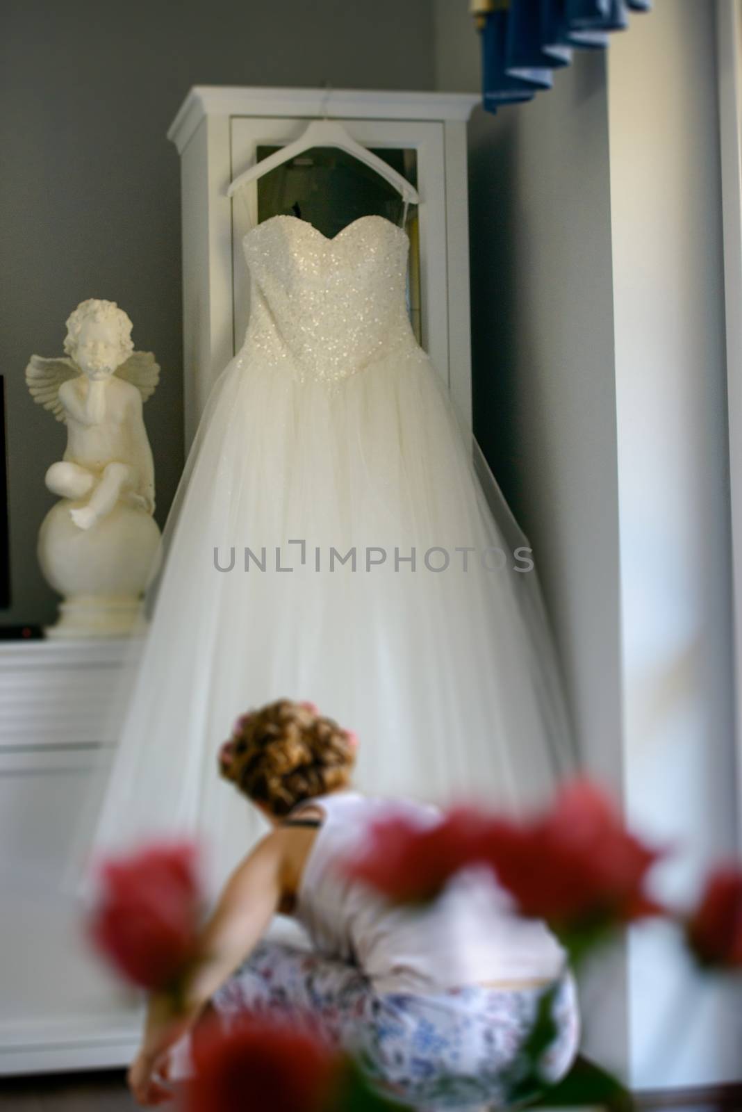 Bridesmaid helping slender bride lacing her wedding white dress, buttoning on delicate lace pattern with fluffy skirt on waist. Morning bridal preparation details newlyweds. Wedding day moments, wear.