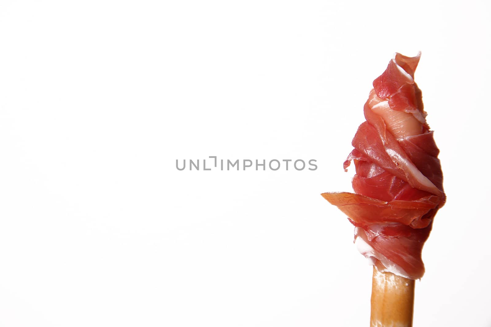 Slice of raw ham rolled up on a breadstick