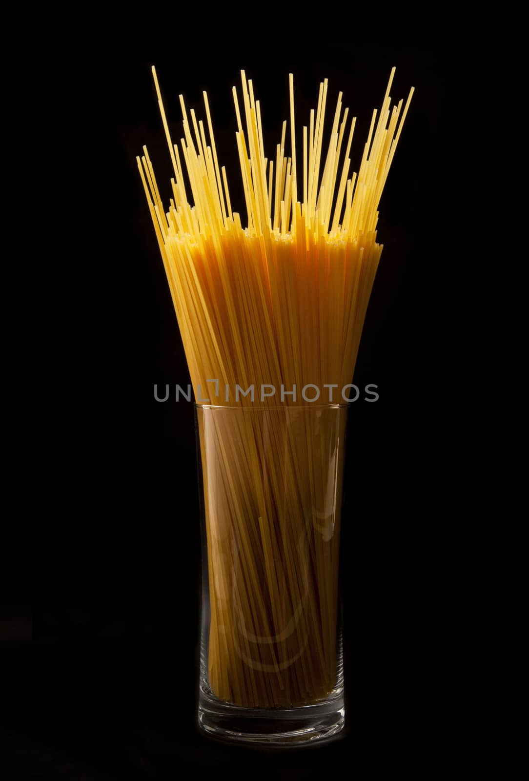 italian pasta in to glass on black background