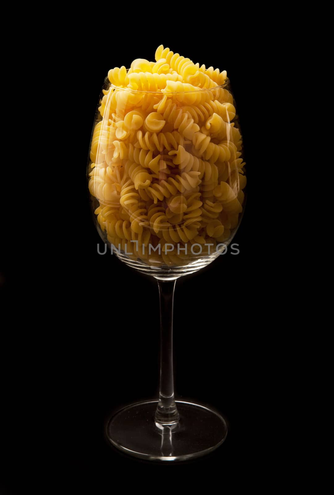 italian pasta in to glass on black background