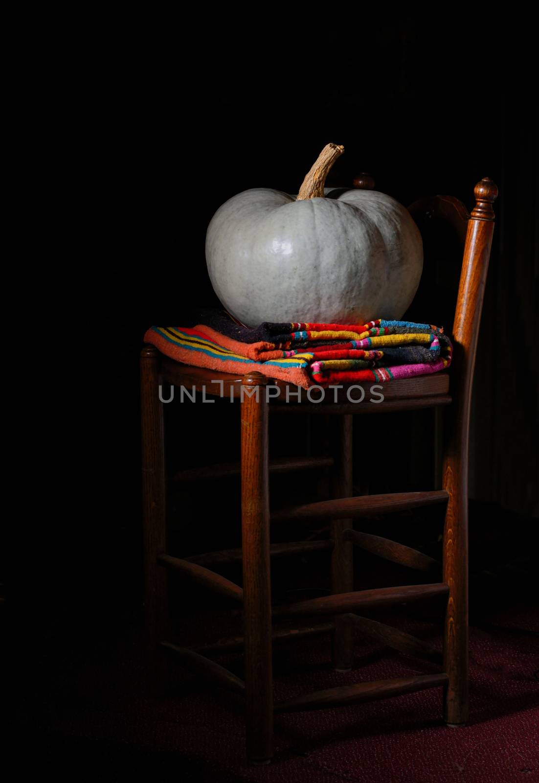 raw pumpkin on rustic chair on black background