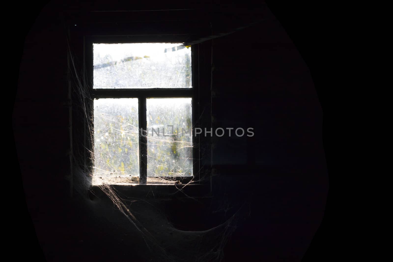 Old dirty window with cobweb around and darkness inside