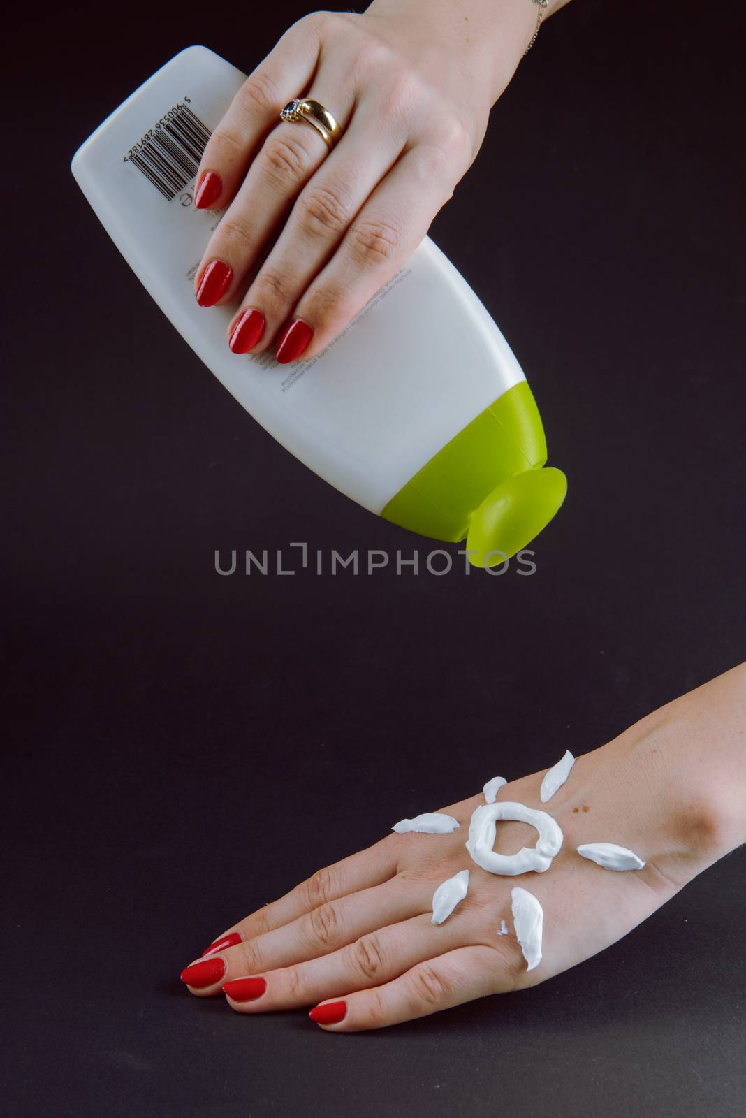 woman applying sunscreen cream on Hand. Red nails.