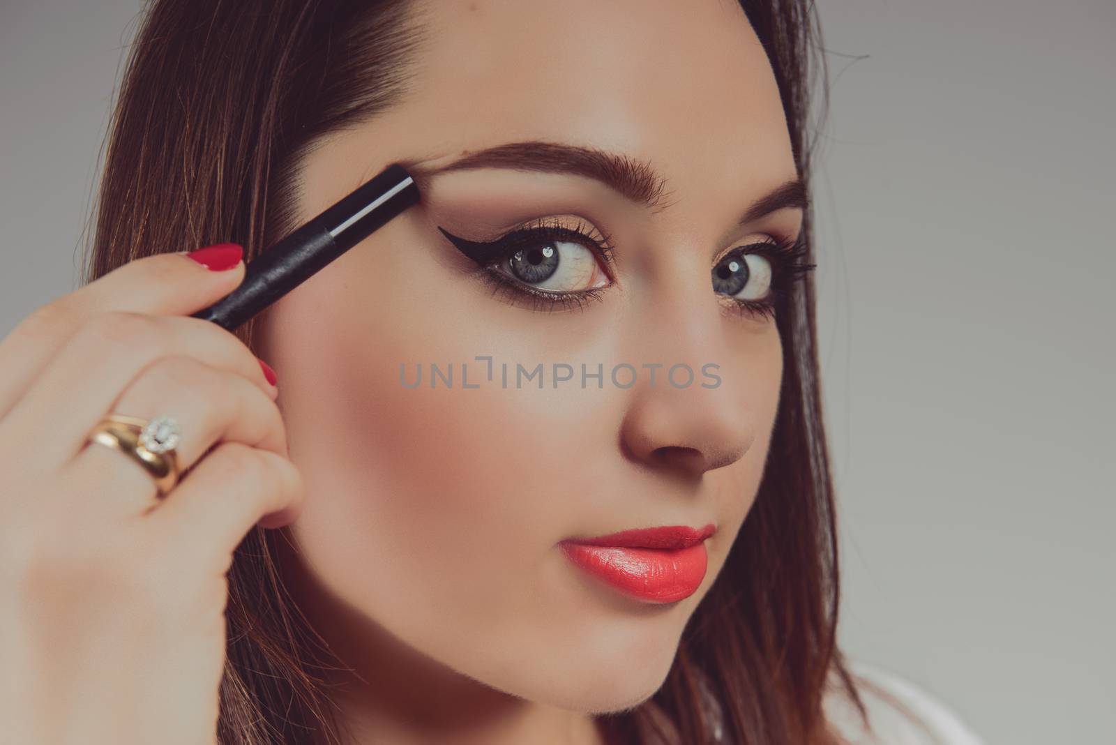 Beauty model teenage girl looking in the mirror and applying mascara make up. Beautiful young woman apply makeup