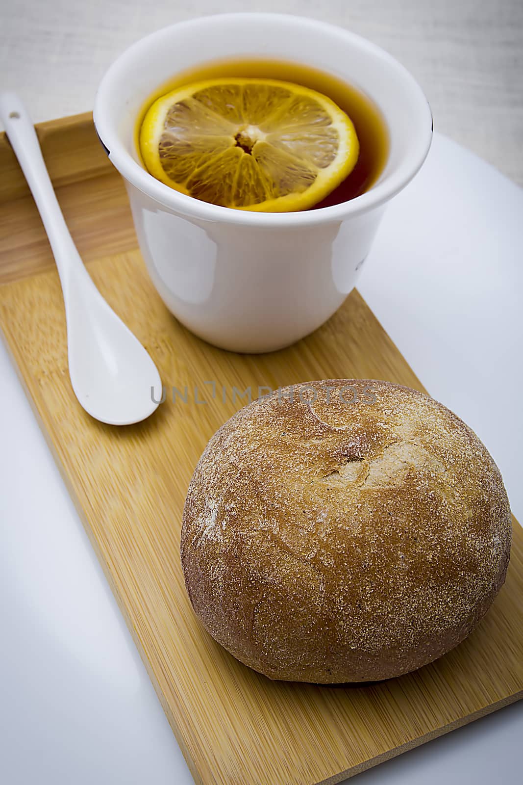 Bun and cup with tea on a wooden tray