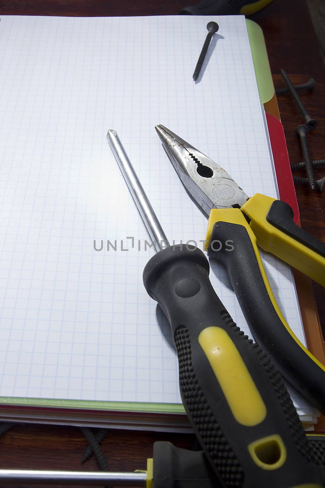 Screwdriver and pliers on a notebook by VIPDesignUSA