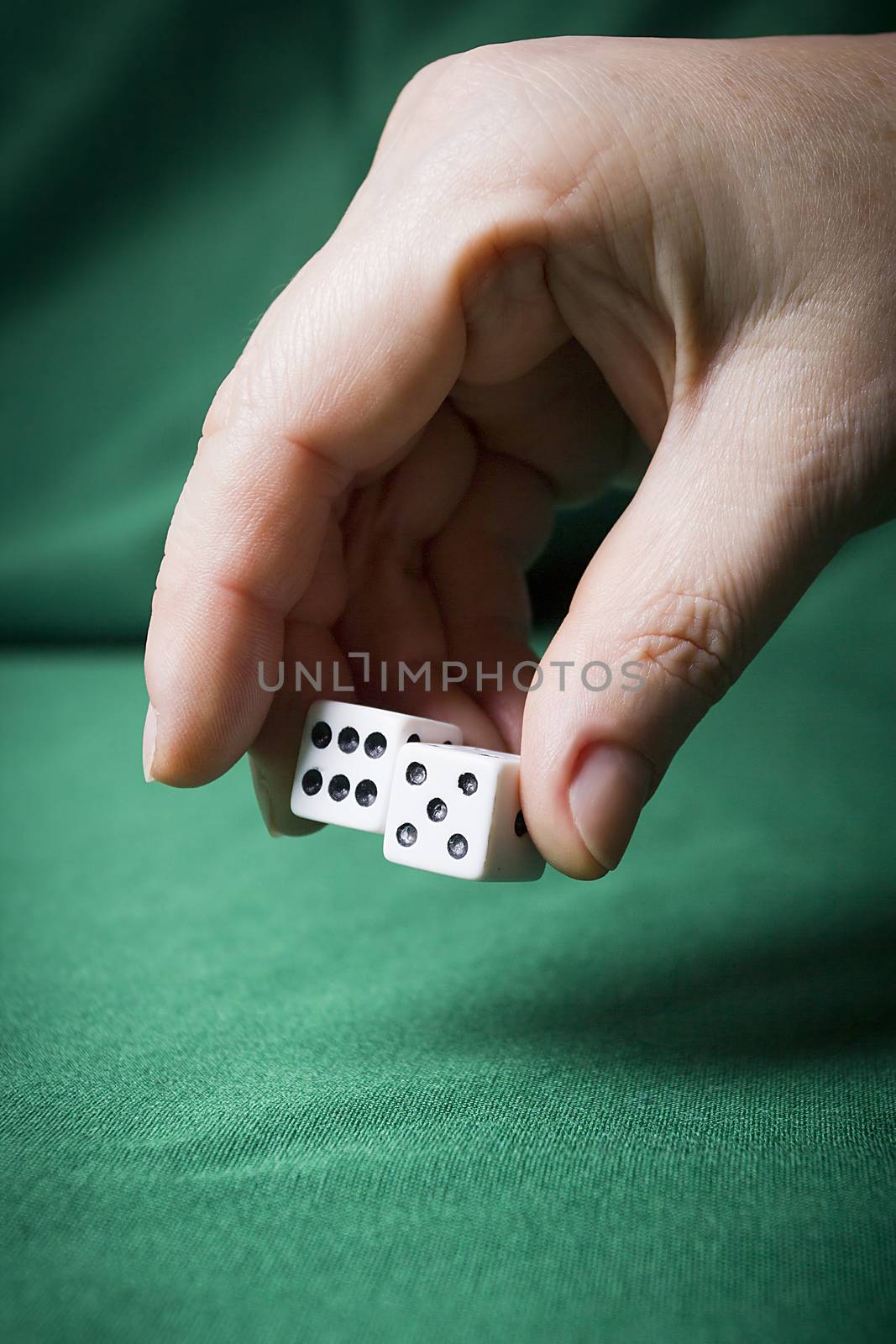 Hand throws dice on a table with green cloth