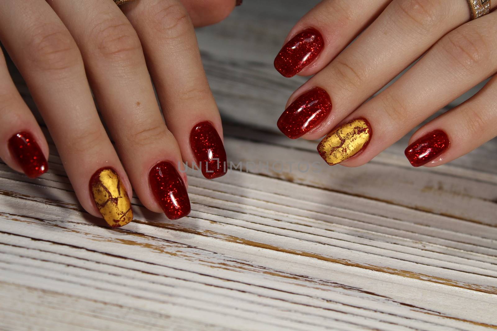 Hands with long artificial manicured nails colored with red nail polish