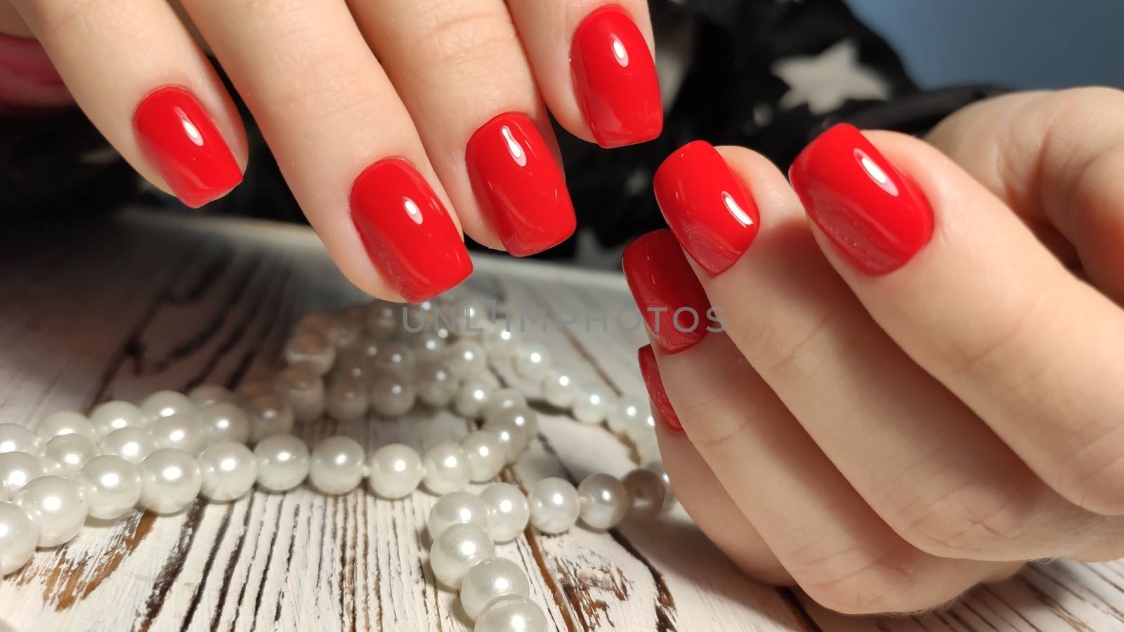 Hands with long artificial manicured nails colored with red nail polish