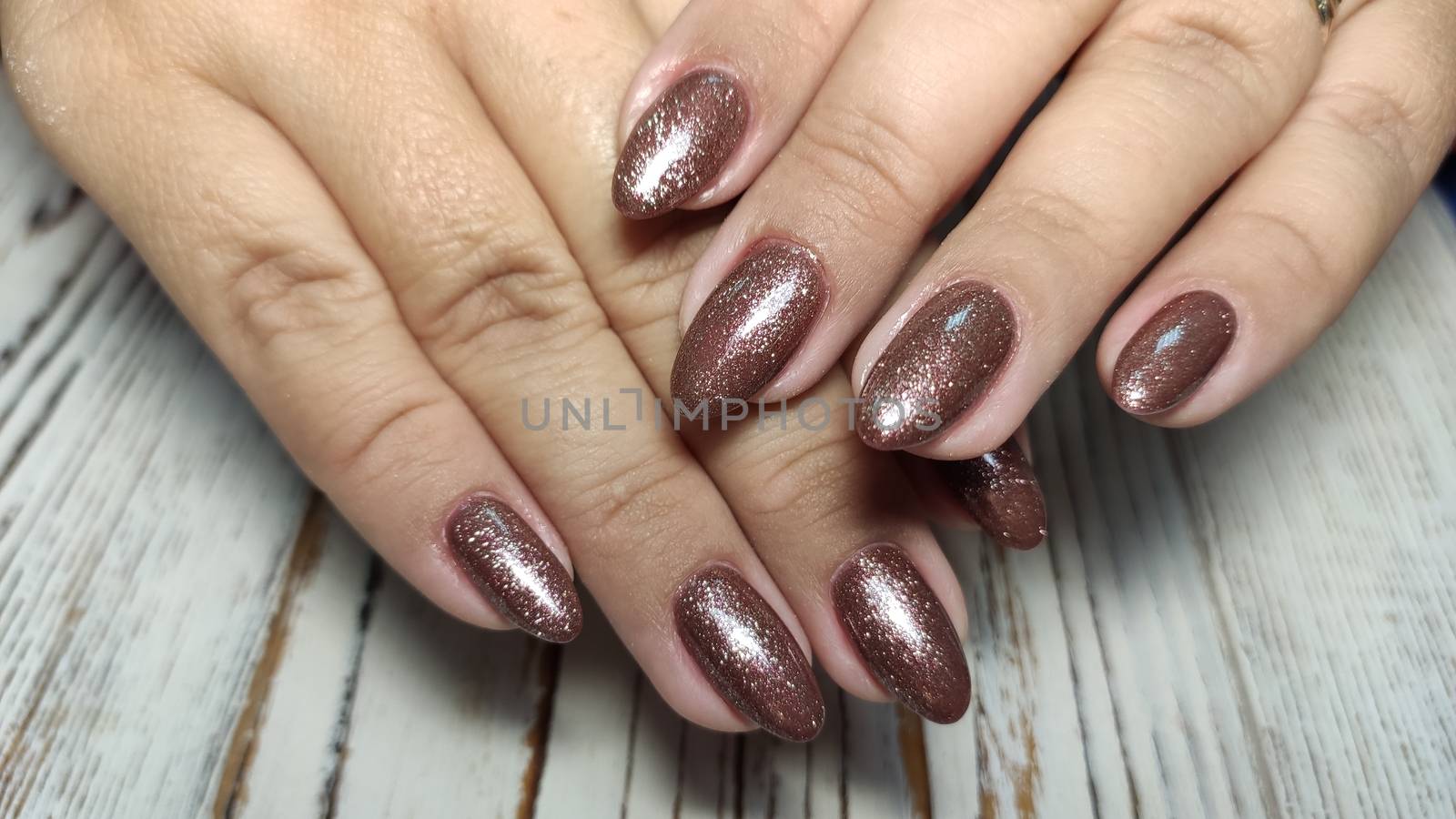 Glamorous luxurious brown crocodile manicure with gold plated women's nails closeup.