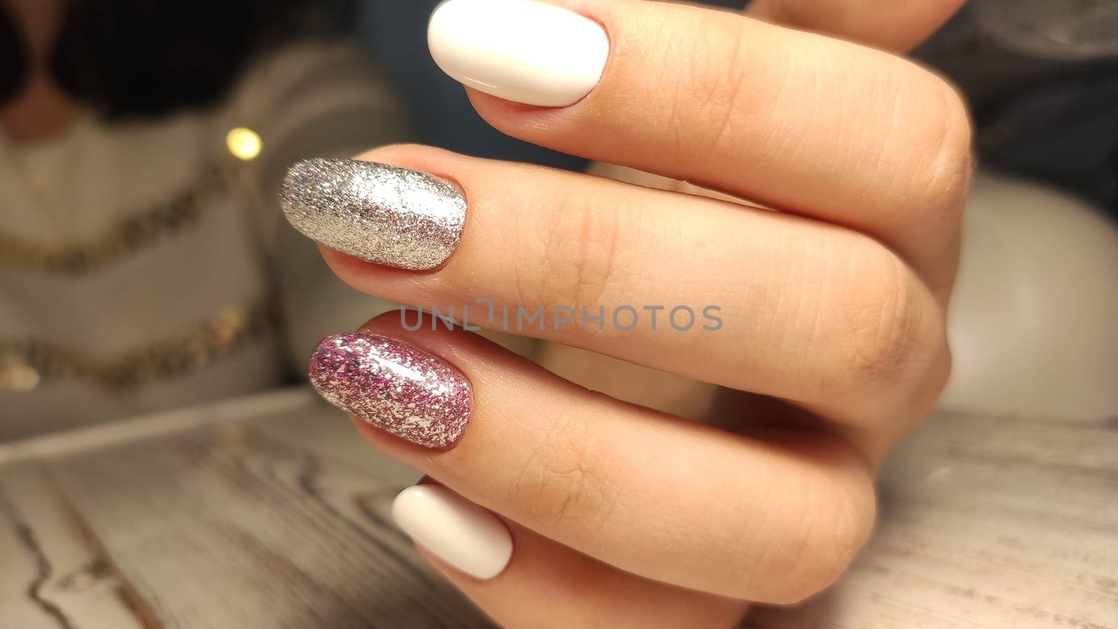 Closeup of hands of a young woman with dark red manicure on nails against white background