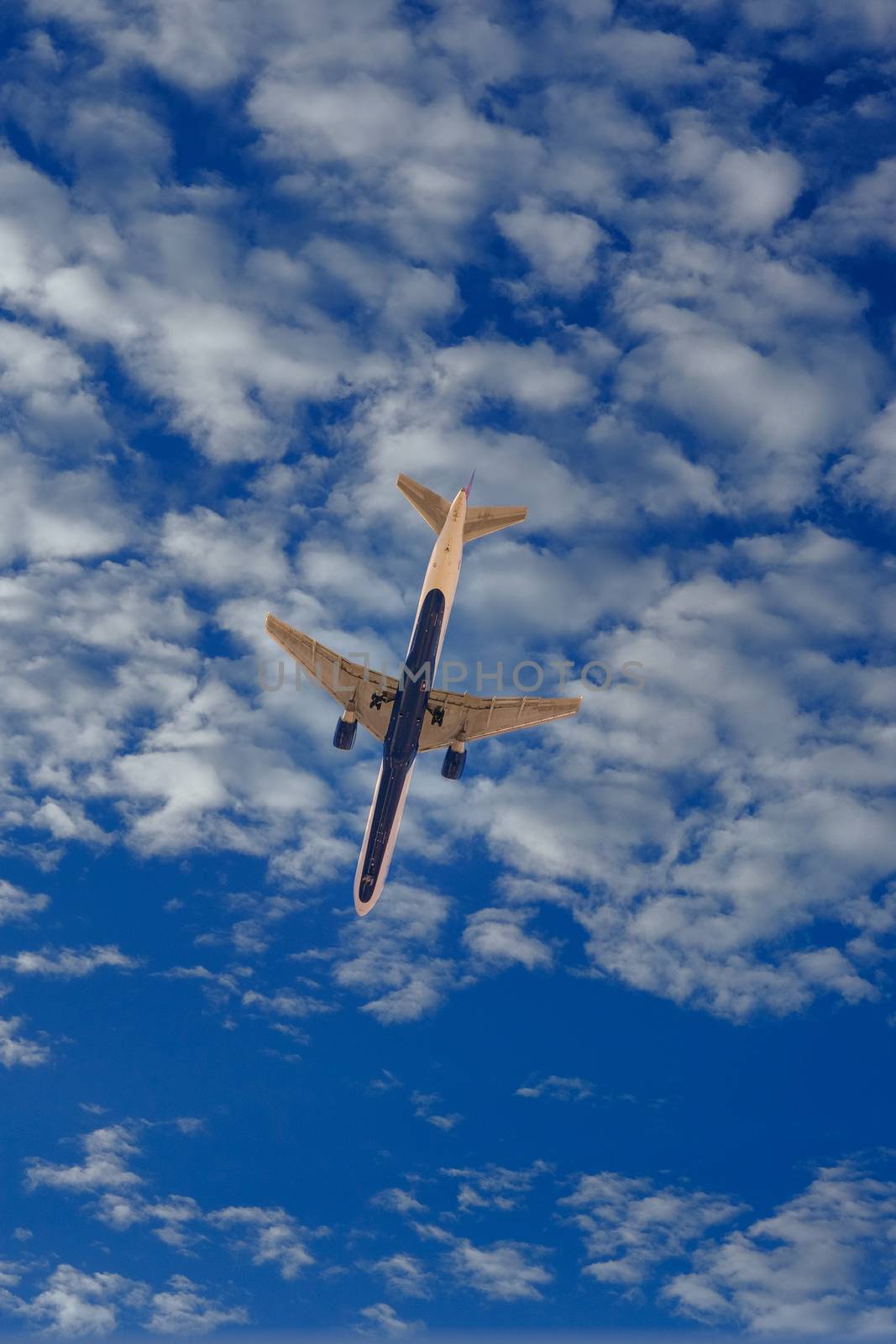 A commercial airplane from below in blue sky