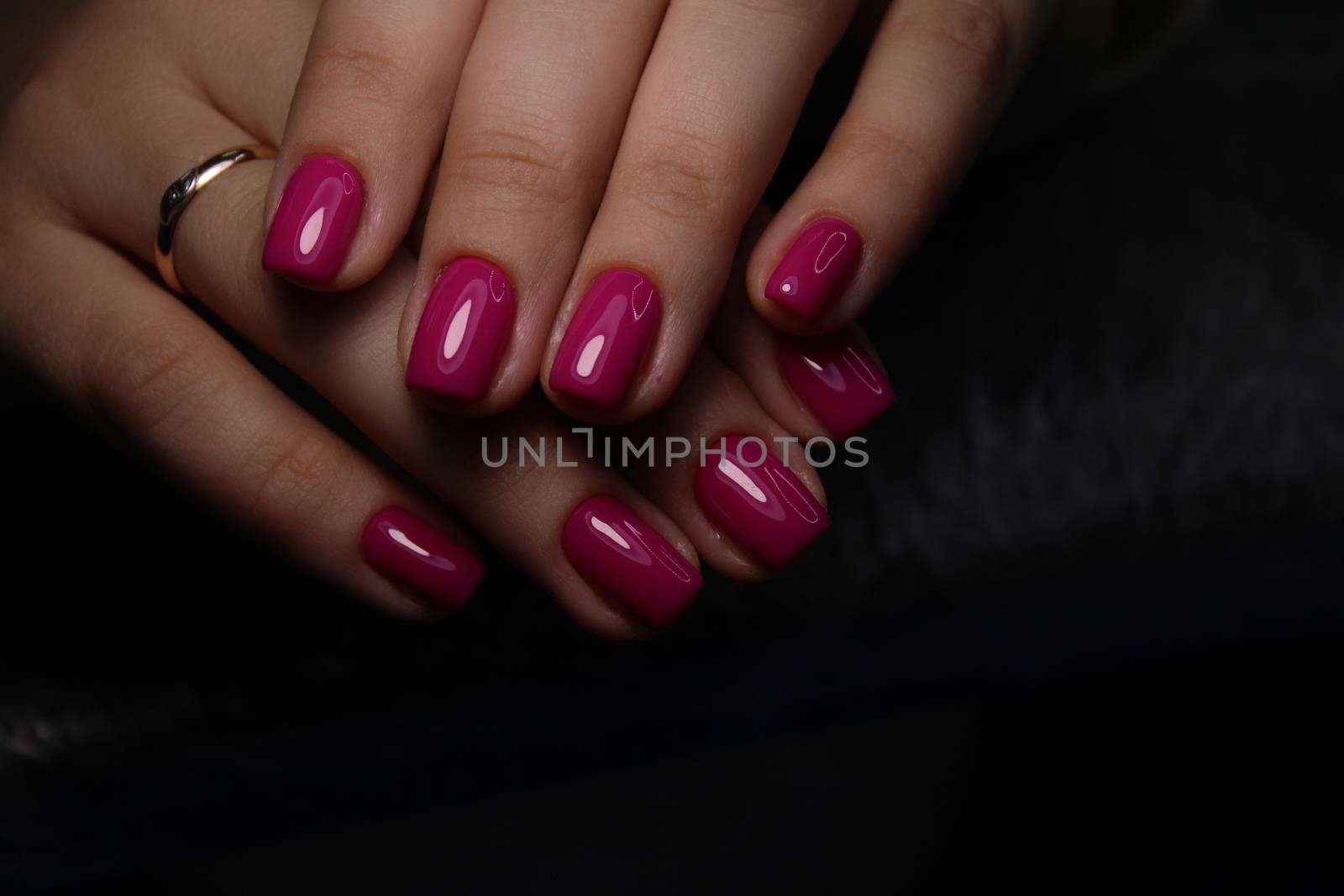 Closeup of hands of a young woman with dark red manicure on nails against white background