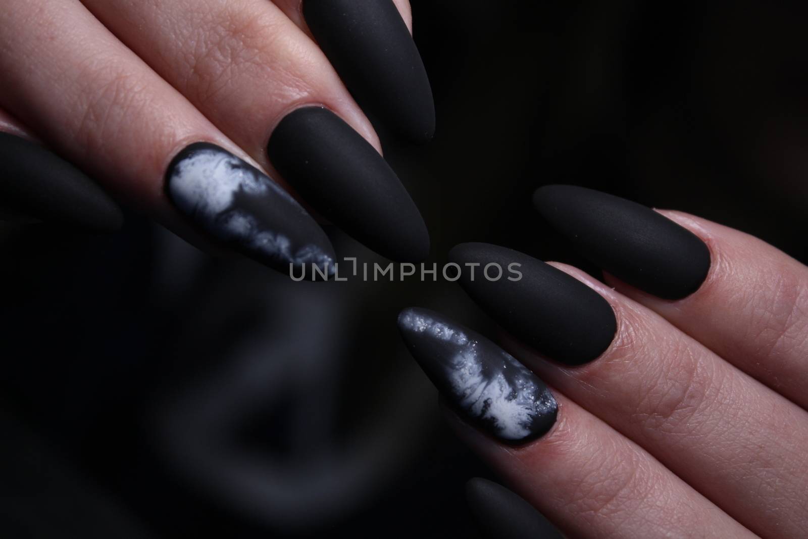 Closeup of hands of a young woman with dark red manicure on nails against white background