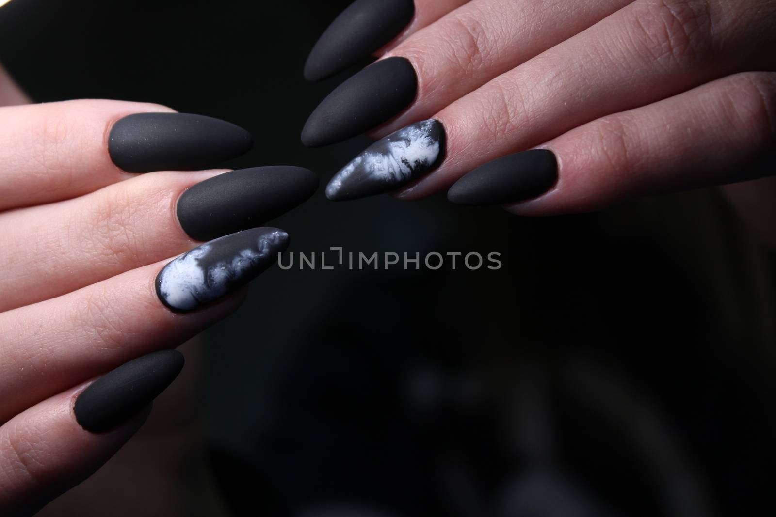 Closeup of hands of a young woman with dark red manicure on nails against white background