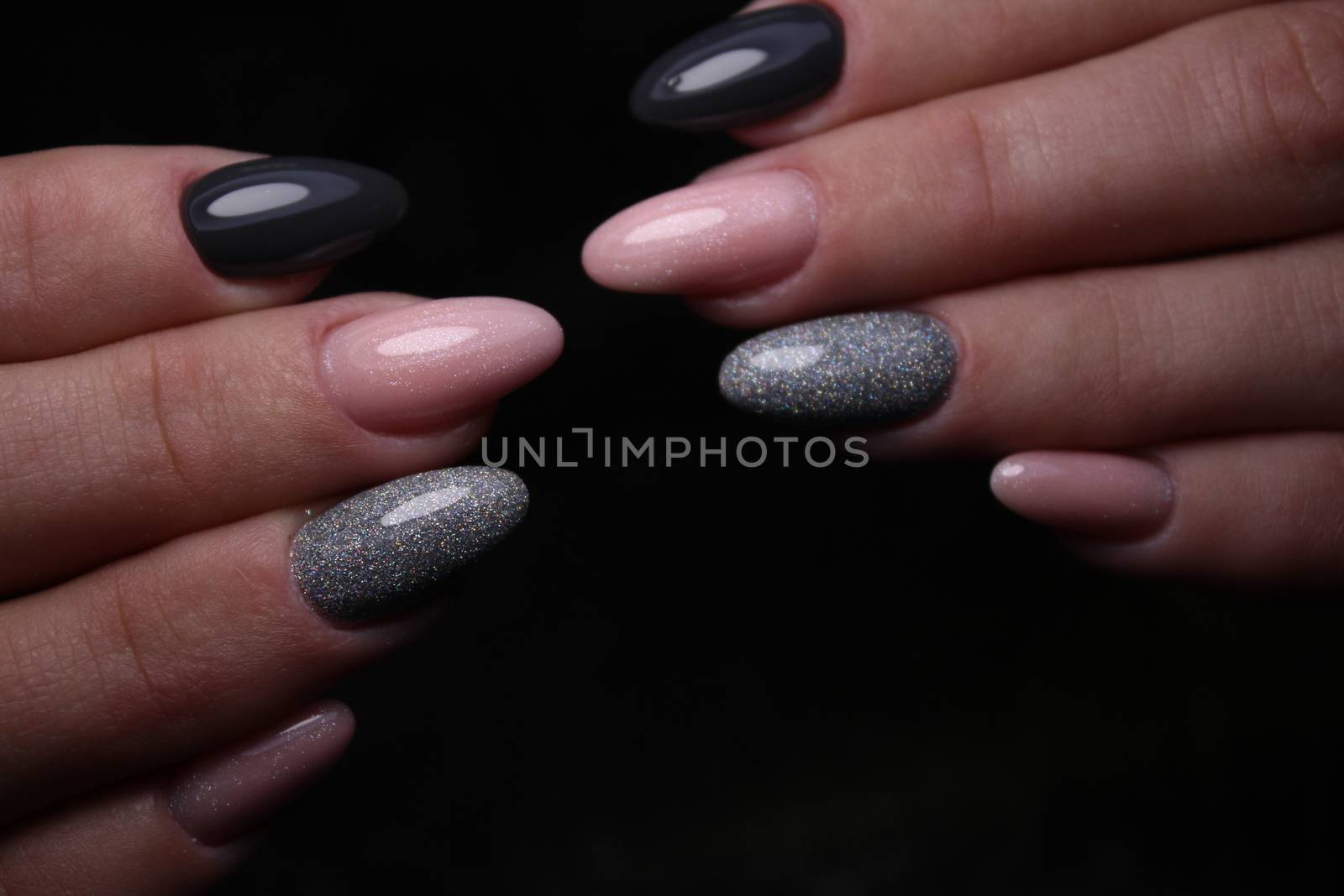 Closeup of hands of a young woman with dark red manicure on nails against white background